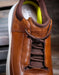Brown leather shoe with brand logo on a blurred background
