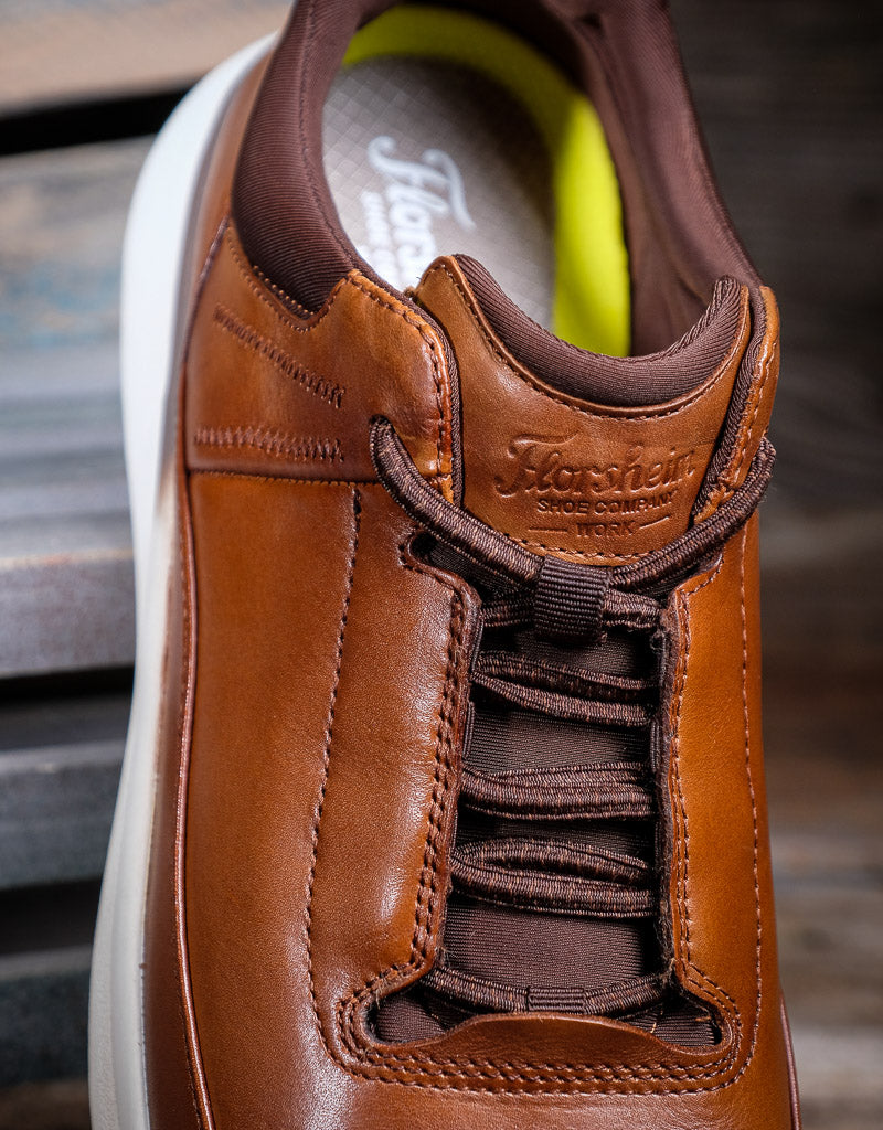 Brown leather shoe with brand logo on a blurred background
