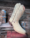 Bone colored cowboy boot with blue stitching on a wooden surface