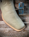 Light bone cowboy boot with tan sole on a wooden surface