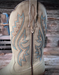 Close-up of an off white cowboy boot with intricate turquoise western stitching on a wooden background.