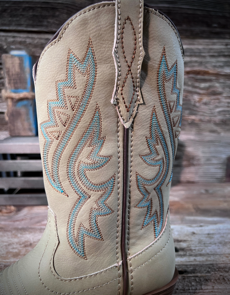 Close-up of an off white cowboy boot with intricate turquoise western stitching on a wooden background.