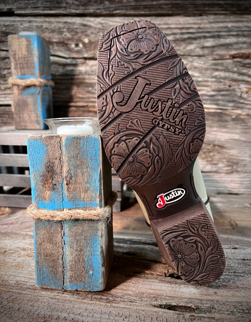 Close-up of a boot sole with 'Justin' branding on a rustic wooden background