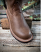 Brown leather boot on a rustic wooden surface