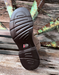 Close-up of a brown shoe sole with a Justin brand logo on a wooden surface