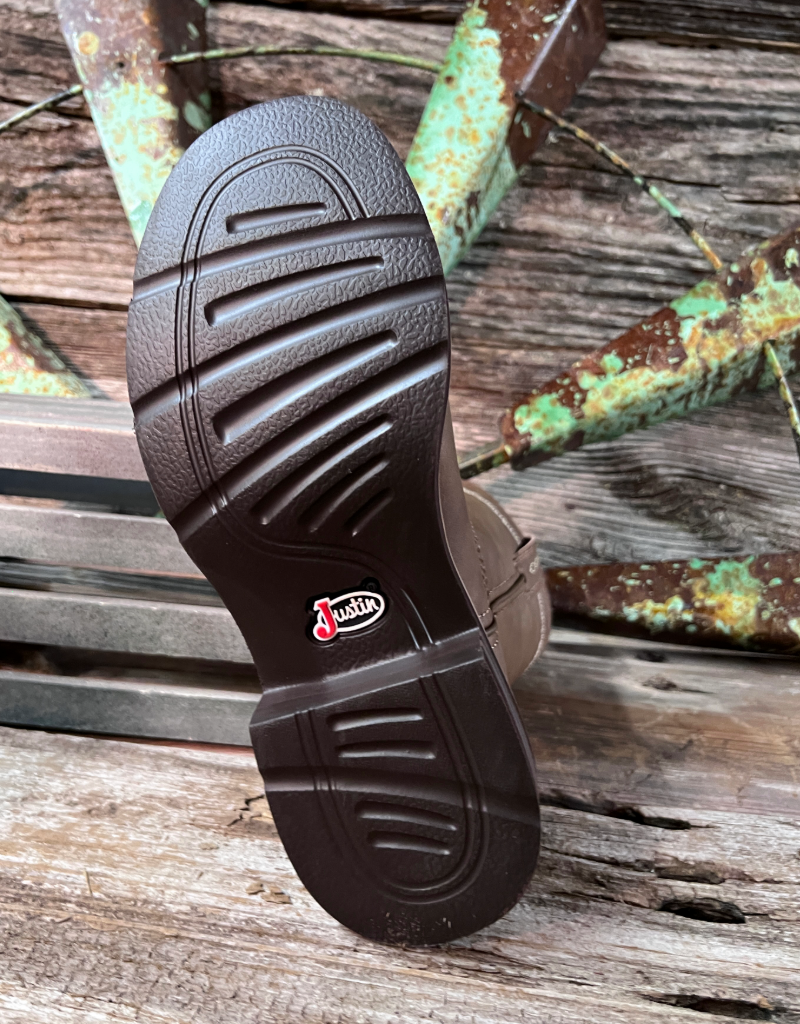 Close-up of a brown shoe sole with a Justin brand logo on a wooden surface