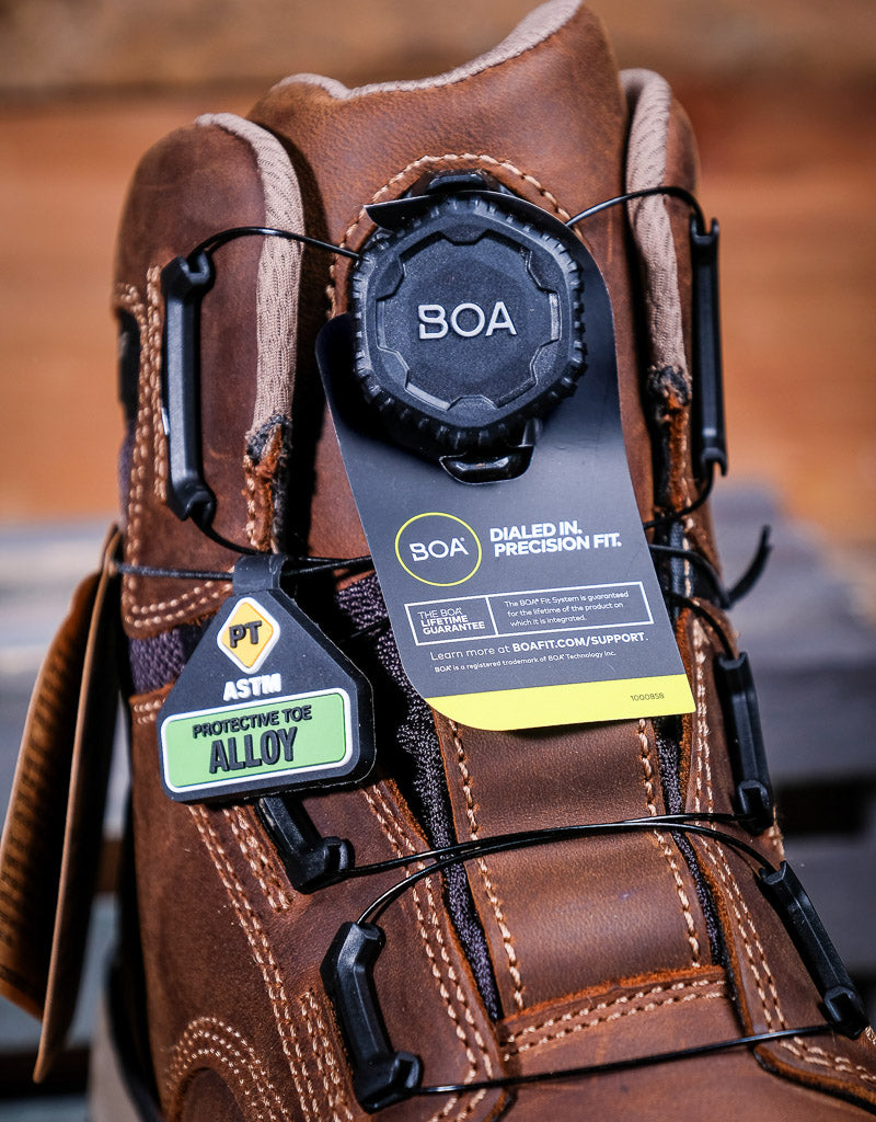 Brown work boot with BOA system and safety certification label on a blurred background