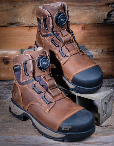 Pair of brown work boots with black soles on a wooden background