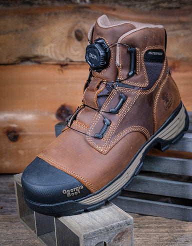 Brown work boot with black sole on a wooden surface