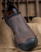 Brown slip-on shoe with black sole on a rustic wooden background