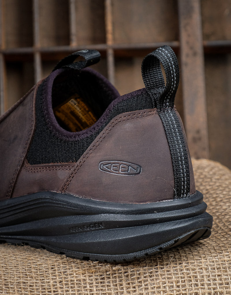 Brown leather shoe with black sole on a rustic wooden background