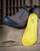 brown leather shoe with a yellow insole in front of it on a rustic background