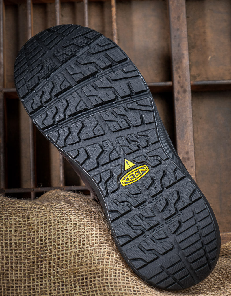 Close-up of a black sole with a yellow KEEN logo on a textured surface.