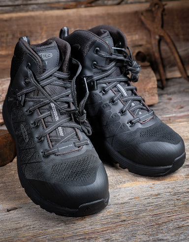 Pair of black tactical boots on a wooden surface