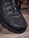 Black hiking style  boot toe with KEEN brand logo on a wooden surface