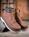 Pair of brown leather work boots with laces on a wooden background
