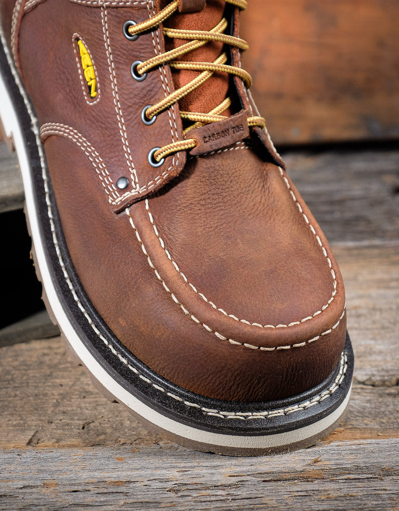 Brown leather boot with yellow laces on a wooden surface