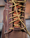 Close-up of a brown leather boot with gold laces and 'Carbon Toe' label.