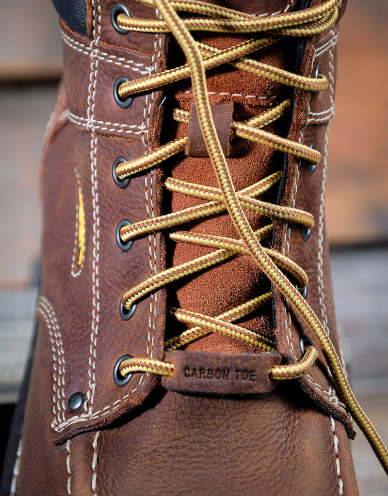 Close-up of a brown leather boot with gold laces and 'Carbon Toe' label.