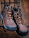 Pair of brown leather work boots with black and grey soles on a wooden background