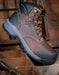 Brown leather boot with black sole on a wooden background