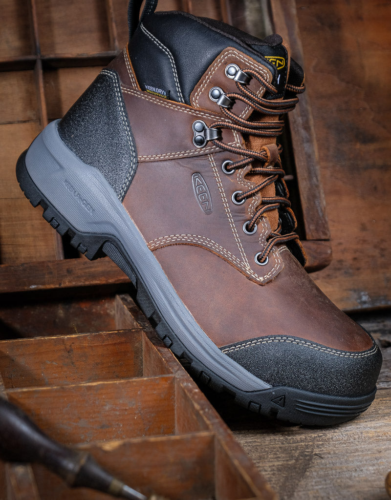 Brown leather boot with black sole on a wooden background