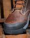 Brown leather boot with black sole on a wooden surface