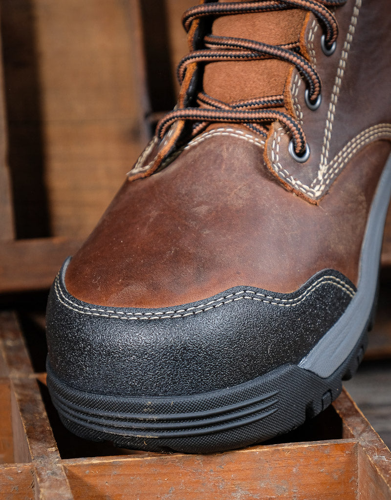 Brown leather boot with black sole on a wooden surface