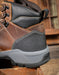 Brown and black hiking boot with gray sole on a wooden surface