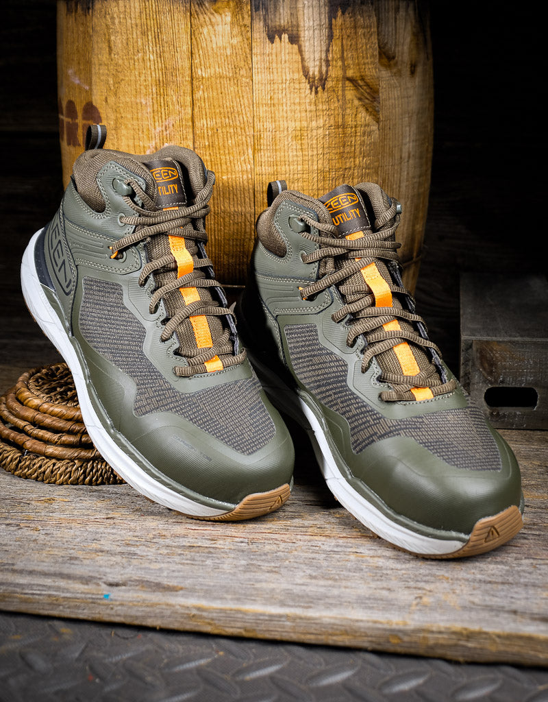 Pair of green hiking boots with orange accents on a wooden surface.