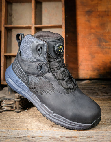 Black boot with gray sole on a wooden surface