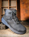 Black boot with gray sole on a wooden surface