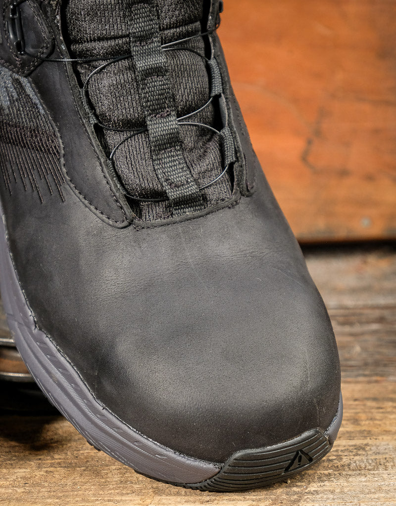 Black boot boot toe on a wooden surface