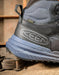 Close-up of a Keen hiking boot on a rustic background with a label that says Keen Dry Waterproof 