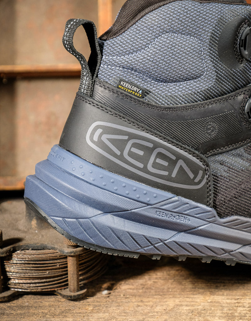 Close-up of a Keen hiking boot on a rustic background with a label that says Keen Dry Waterproof 