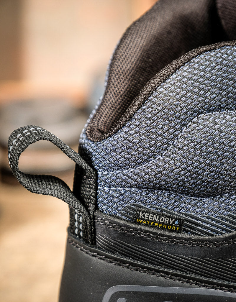 Close-up of a KEEN boot with 'KeenDry' and 'Waterproof' labels on a blurred background