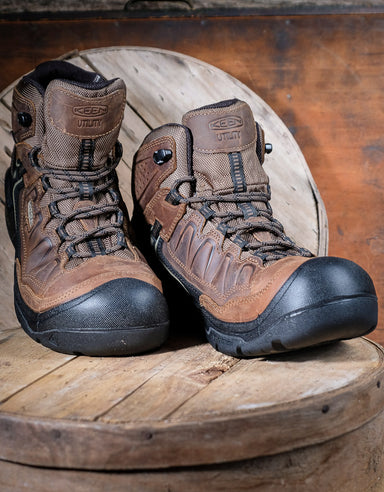 Pair of brown hiking boots with black soles on a wooden surface