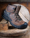 Brown hiking boot with black sole on a wooden surface