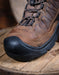 Brown hiking boot with black sole on a wooden surface
