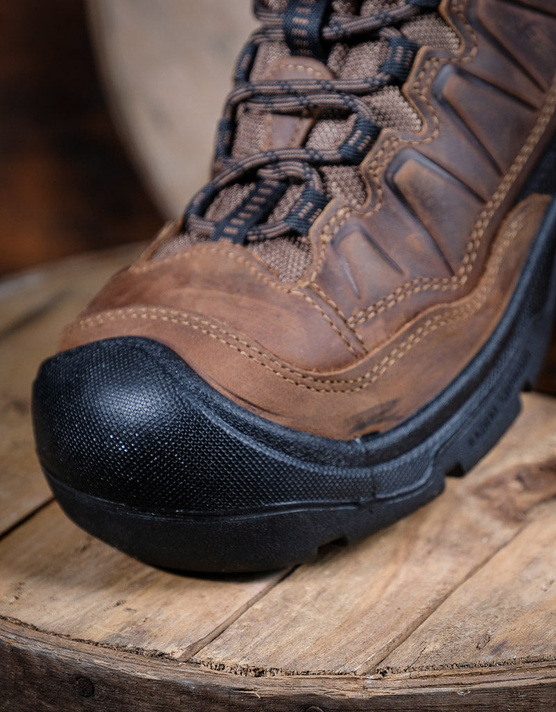 Brown hiking boot with black sole on a wooden surface