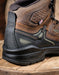 Close-up of a brown and black work boot on a wooden surface