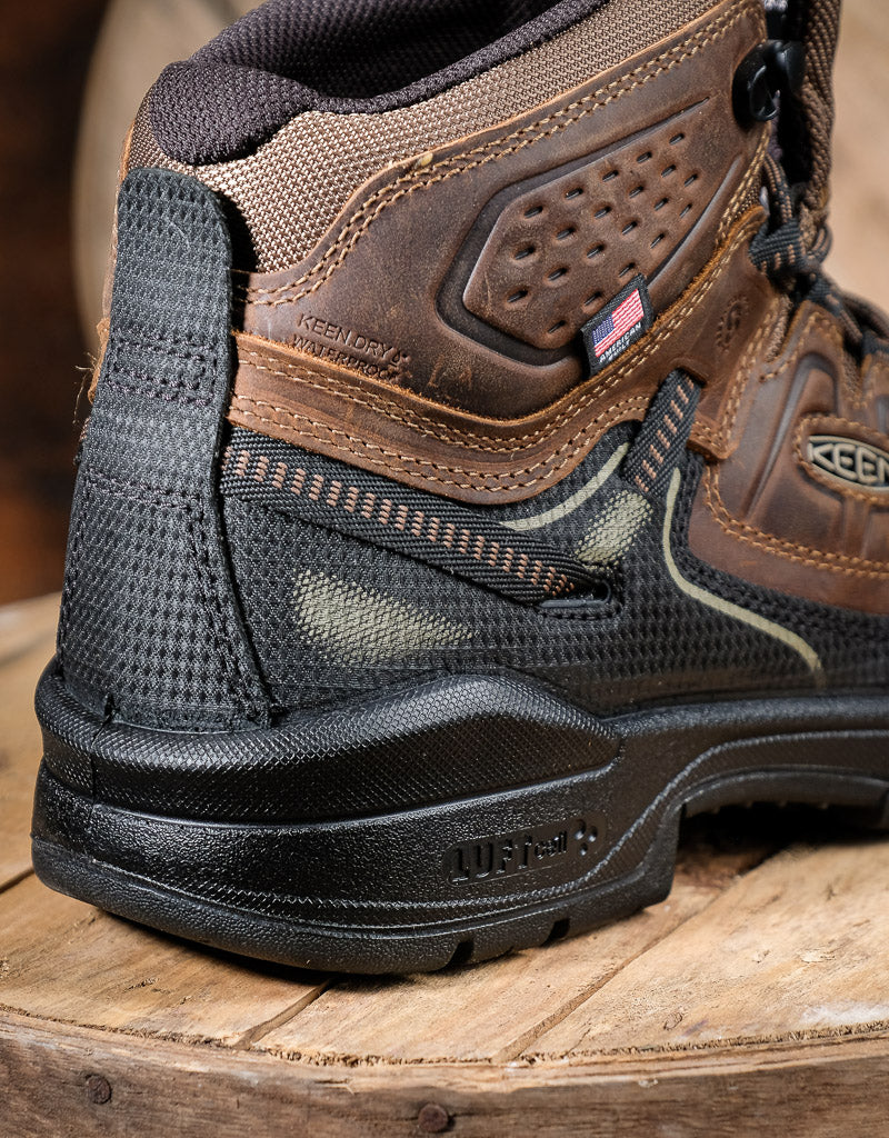Close-up of a brown and black work boot on a wooden surface