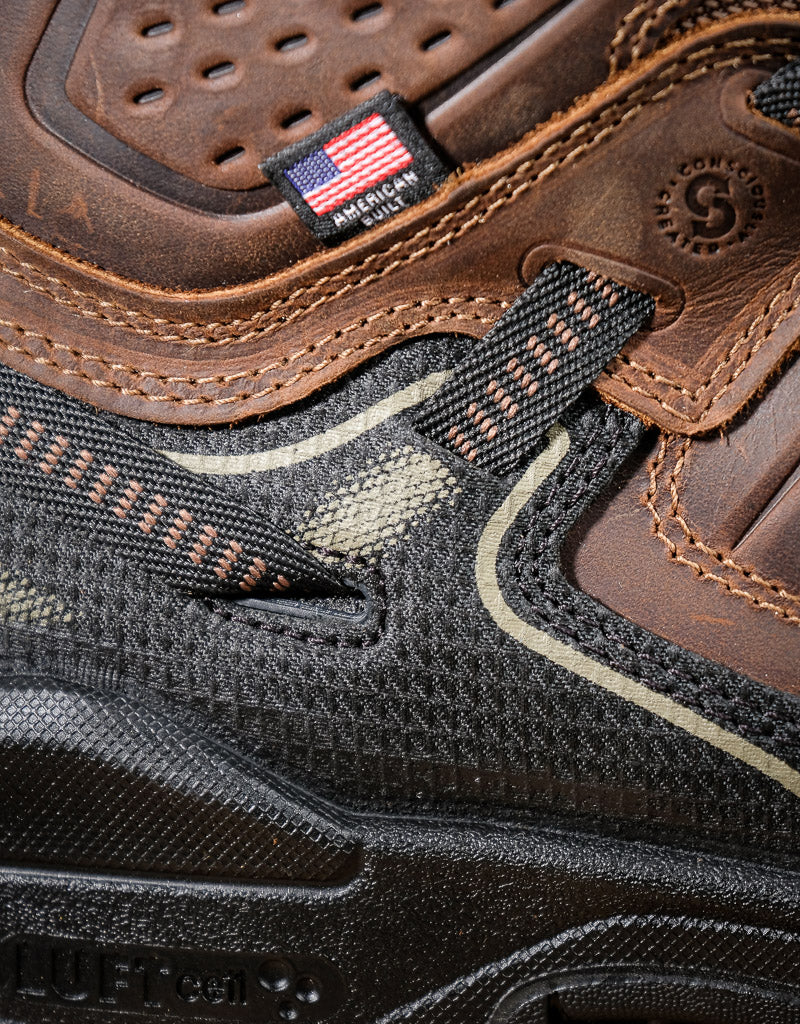 Close-up of a brown and black shoe with a visible American Built logo and American flag patch.