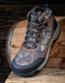 Camouflage hiking boot on a wooden surface with a rustic background