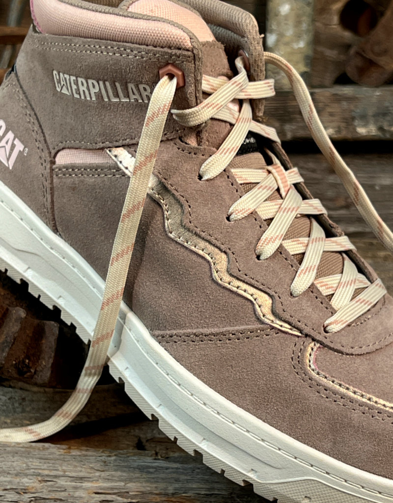Brown and pink sneaker with white sole on a wooden surface, featuring the Caterpillar brand.
