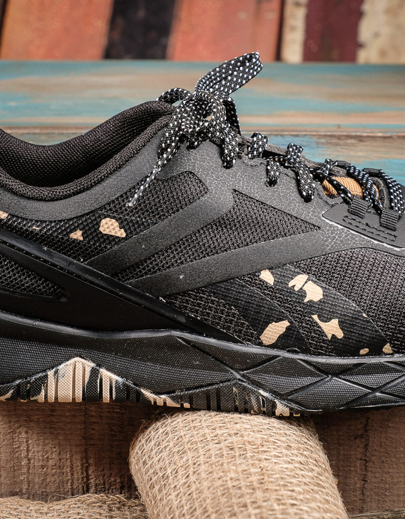 side details on black athletic shoe camo pattern is peeking from the sole