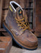 Brown leather boot with yellow laces on a wooden background