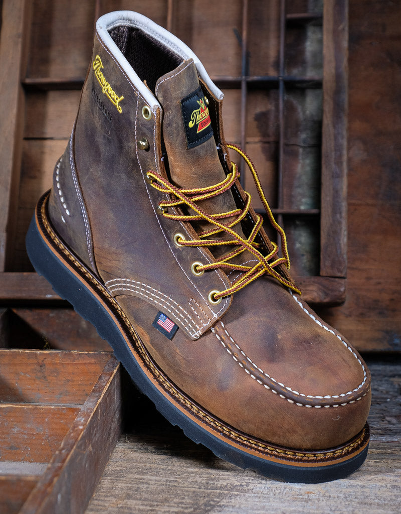 Brown leather boot with yellow laces on a wooden background