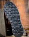 Close-up of a shoe sole with tread pattern and Thorogood brand logo on a wooden background