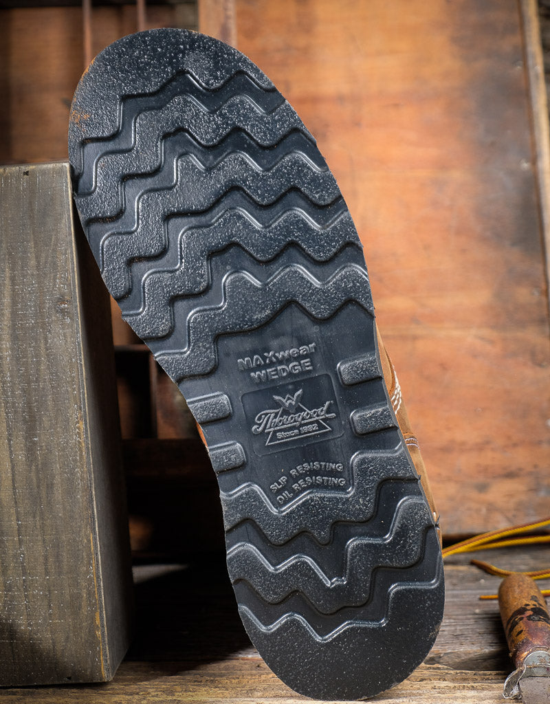Close-up of a shoe sole with tread pattern and Thorogood brand logo on a wooden background